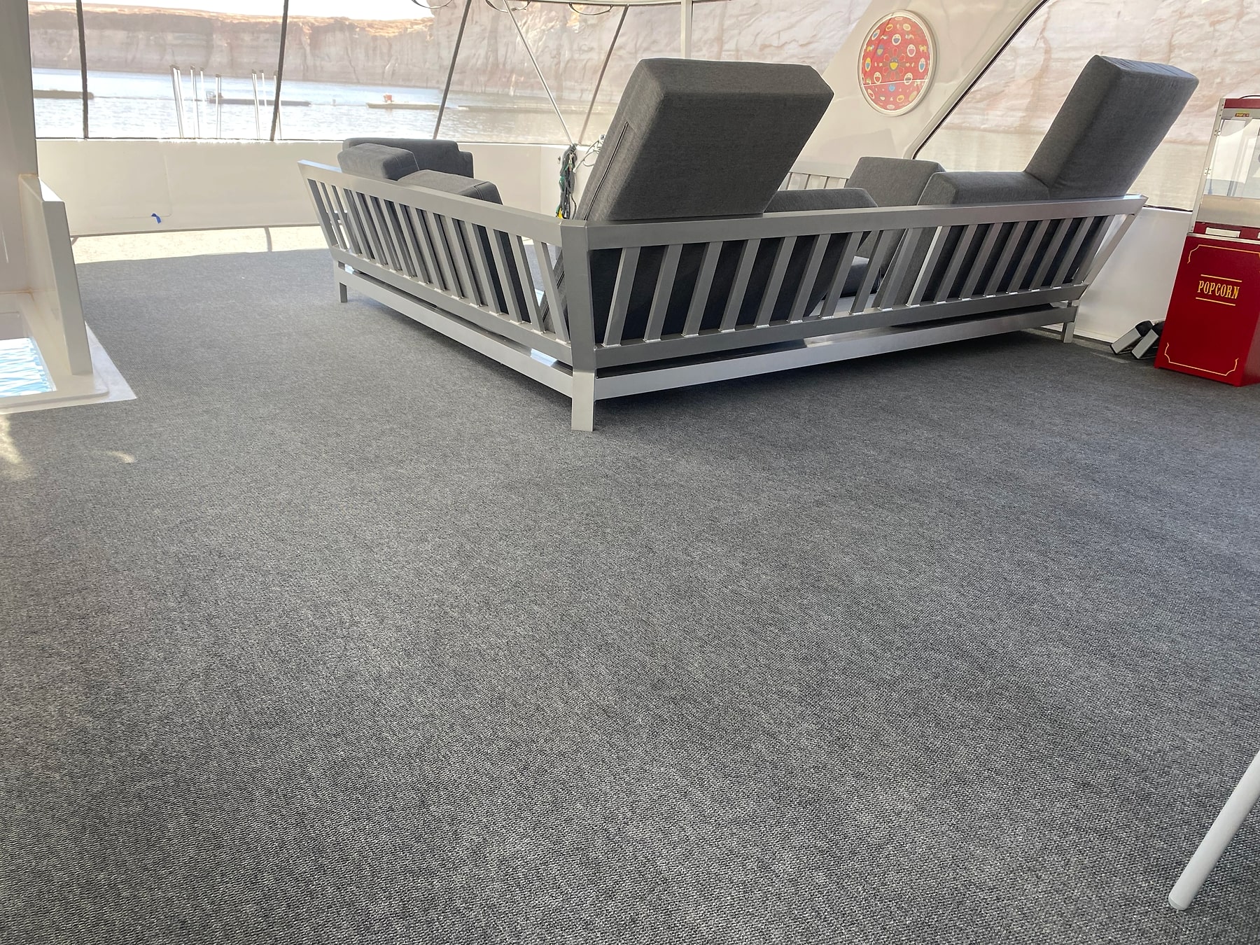 Gray carpeted deck and seating area inside a houseboat